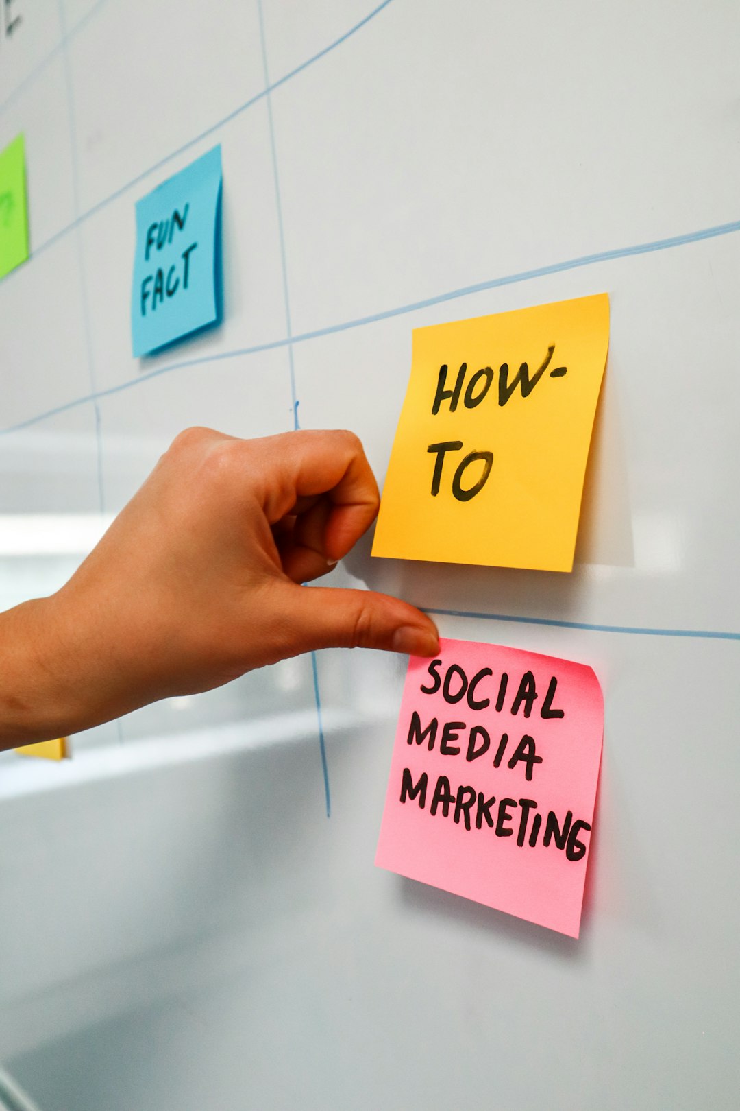 Person sticking a post-it on a white board with the words "Social Media Marketing" written on it